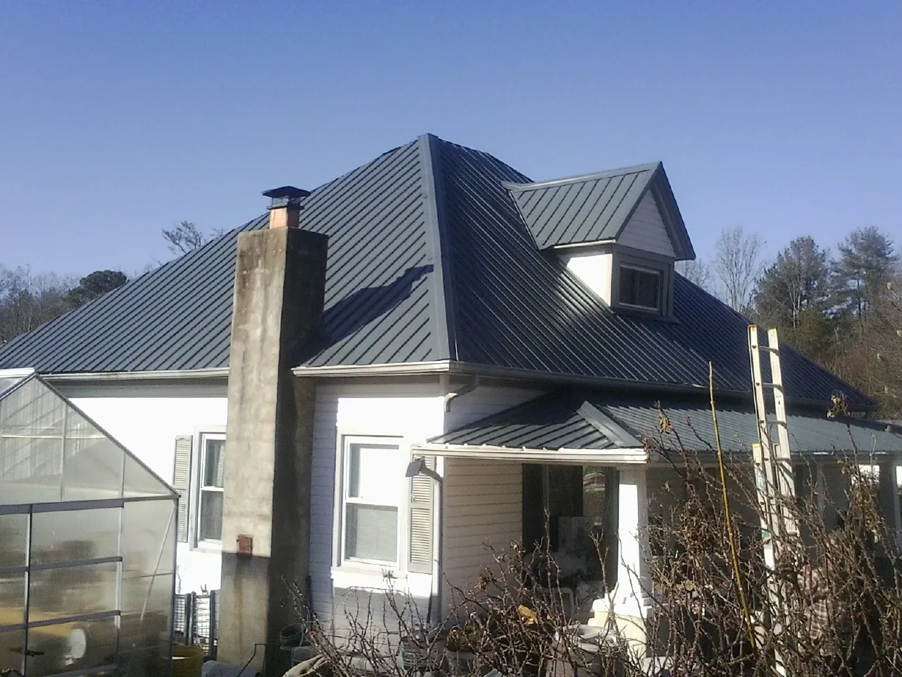 Dark blue standing seam metal roof on a white farmhouse with dormer — Slate & Tile Roof Repair by Roofing Brothers in Richmond Hill