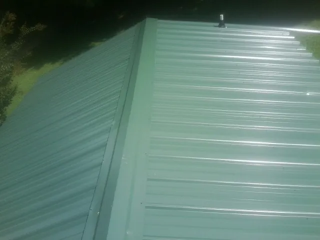 New green metal panels meeting at the ridge of a roof — Flat Roof Repair work by our crew in Richmond Hill