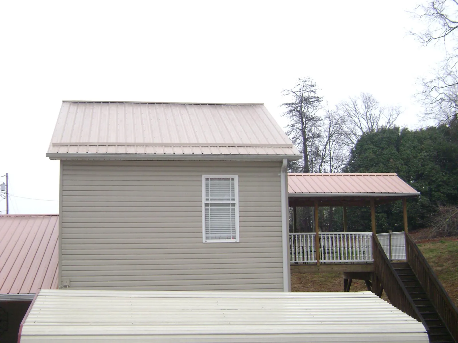 Tan metal roofs on a two story addition and attached porch, from a Roof Replacement job in Richmond Hill