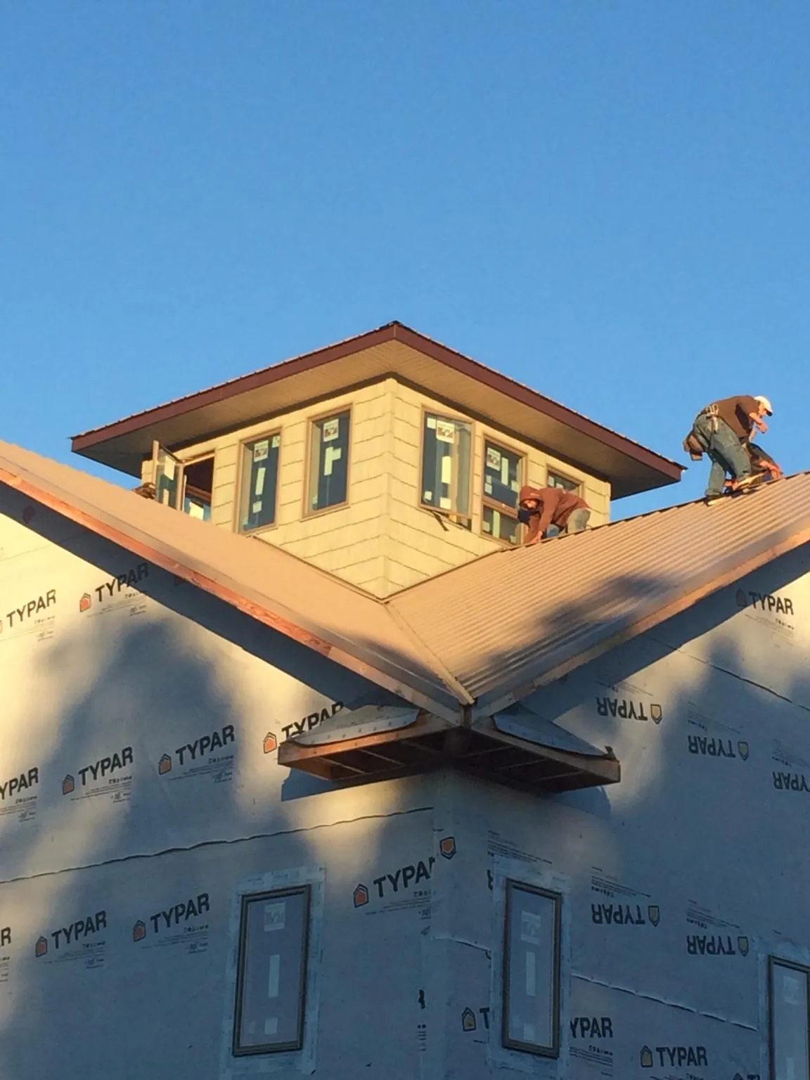 Roofers working around a rooftop cupola on a new metal roof at sunset — Roof Waterproofing in Richmond Hill by Roofing Brothers